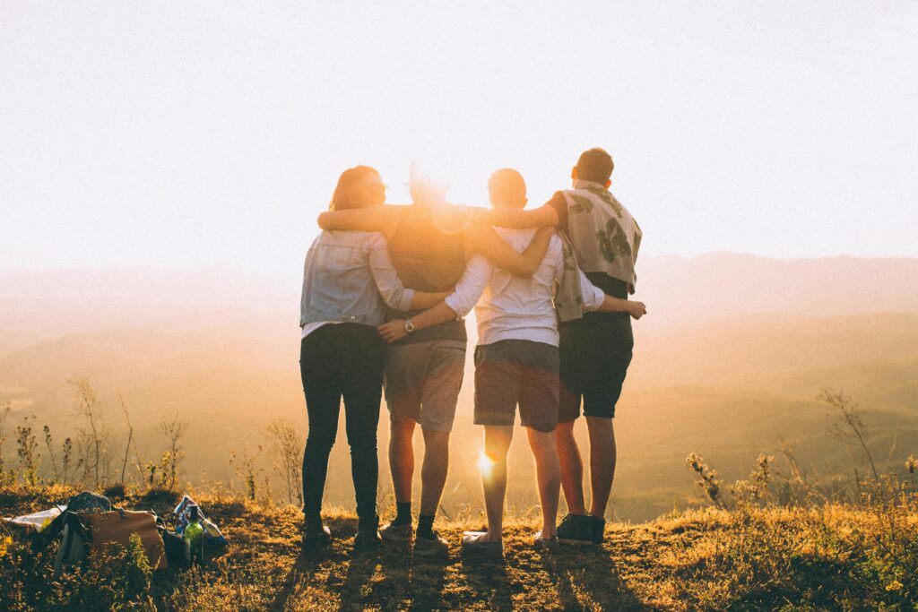 Gruppo di giovani che osserva il sole all’orizzonte, simbolo di futuro e nuove opportunità