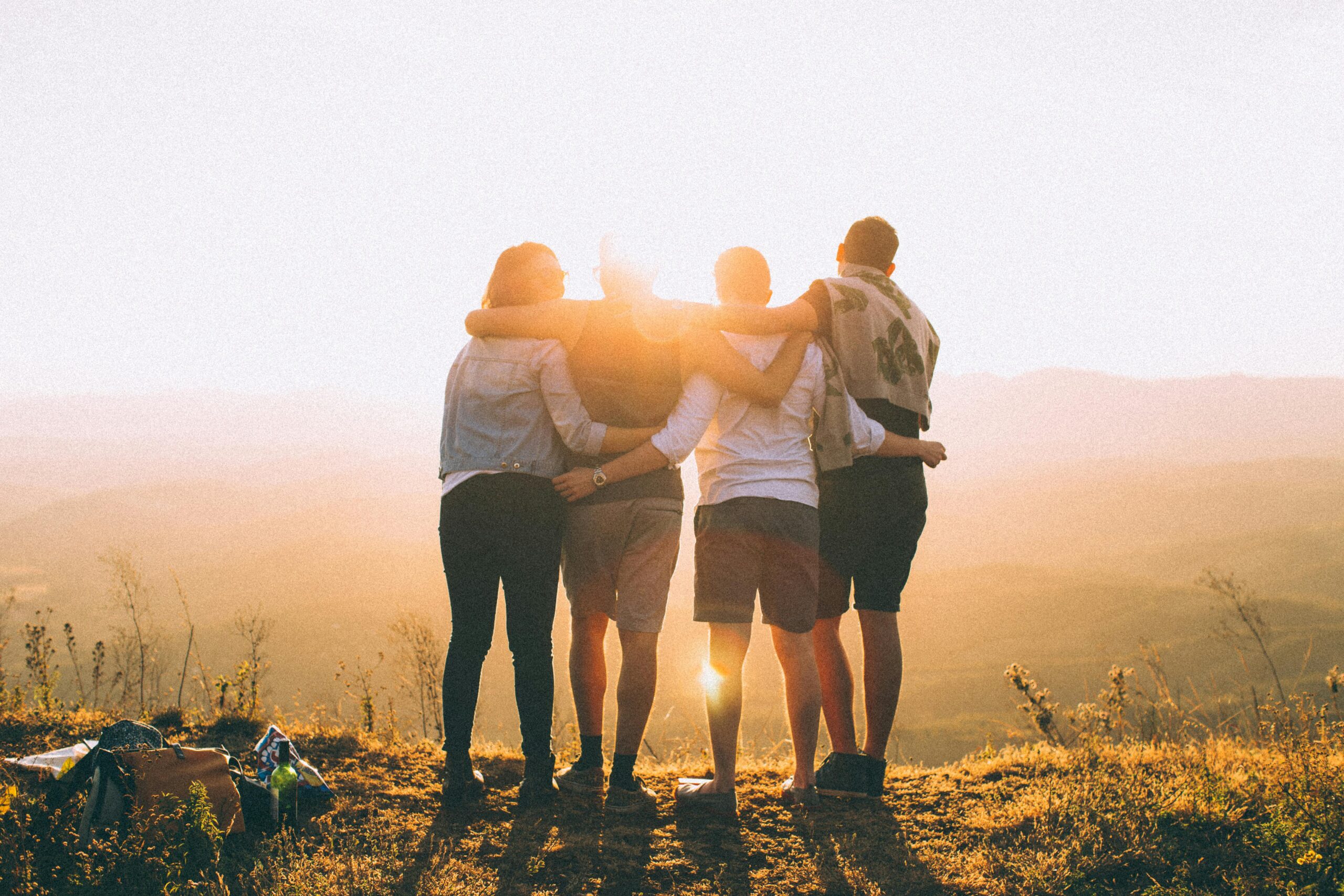 Gruppo di giovani che osserva il sole all’orizzonte, simbolo di futuro e nuove opportunità