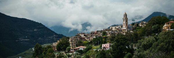 A stunning view of a hilltop village in Lazio, Italy under a moody sky, surrounded by lush nature.