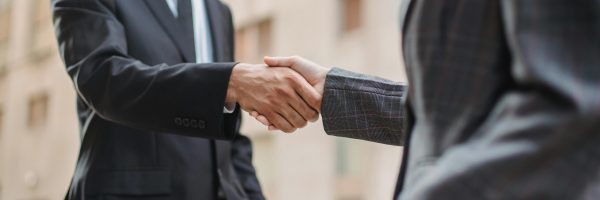Business professionals greeting each other with a handshake outdoors, symbolizing partnership.