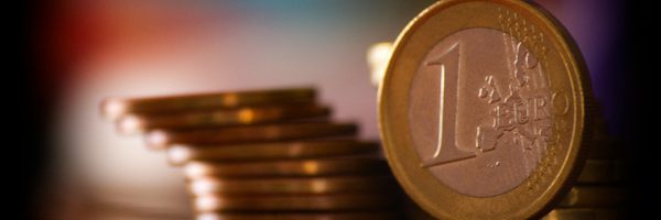 A close-up shot of stacked euro coins with a blurred colorful background, representing financial concepts.